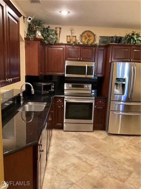 17560 Brickstone Loop, Fort Myers, FL 33967 - kitchen with appliances with stainless steel finishes, a sink, and dark stone counters