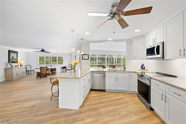 636 Park Shore Dr, Naples, FL 34103 - kitchen featuring stainless steel appliances, a peninsula, ceiling fan, a breakfast bar area, and white cabinetry