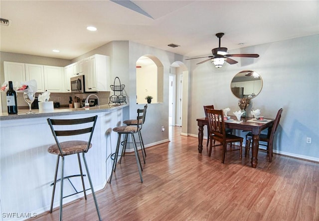 1129 NW 19th Ave, Cape Coral, FL 33993 - kitchen featuring stainless steel microwave, arched walkways, a breakfast bar area, baseboards, and ceiling fan