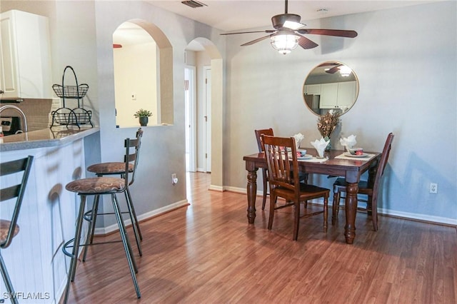 1129 NW 19th Ave, Cape Coral, FL 33993 - dining space featuring arched walkways, wood finished floors, a ceiling fan, and baseboards