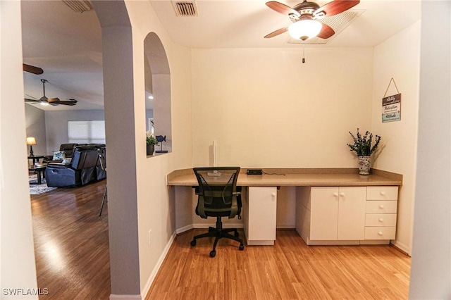 1129 NW 19th Ave, Cape Coral, FL 33993 - office featuring a ceiling fan, light wood-style floors, built in desk, arched walkways, and baseboards