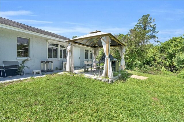 2907 Ashburn St, Lehigh Acres, FL 33972 - rear view of property featuring a gazebo, a lawn, stucco siding, and a patio area