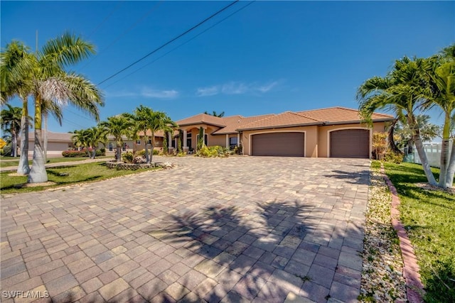141 SW 39th St, Cape Coral, FL 33914 - mediterranean / spanish-style home with stucco siding, a garage, decorative driveway, a tile roof, and a front yard