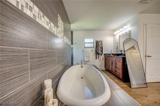 141 SW 39th St, Cape Coral, FL 33914 - bathroom featuring vanity, a jetted tub, and wood finished floors