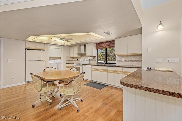 7836 Grande Pine Rd, Bokeelia, FL 33922 - kitchen with washing machine and clothes dryer, white appliances, a ceiling fan, light wood-style floors, and dark countertops