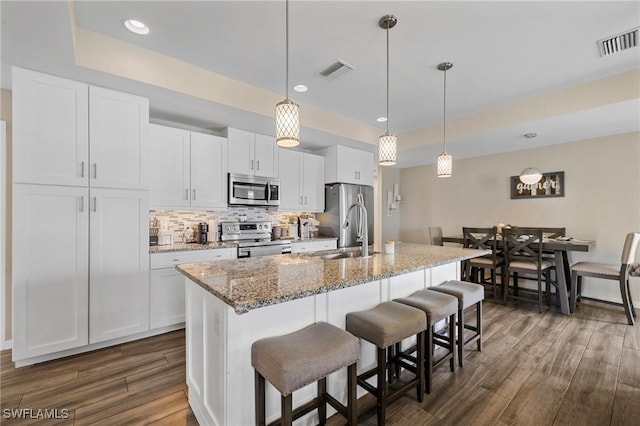 1929 NW 18th St, Cape Coral, FL 33993 - kitchen featuring stainless steel appliances, a sink, dark wood finished floors, an island with sink, and a kitchen breakfast bar