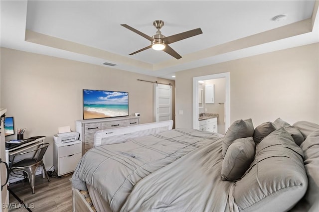 1929 NW 18th St, Cape Coral, FL 33993 - bedroom with a raised ceiling, a barn door, light wood finished floors, ensuite bathroom, and a ceiling fan