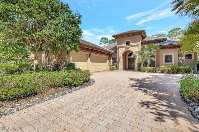 7748 Classics Dr, Naples, FL 34113 - mediterranean / spanish house featuring stucco siding, an attached garage, and decorative driveway