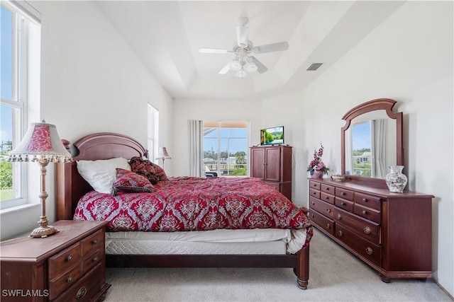 2871 Bracci Dr, Saint James City, FL 33956 - bedroom with light carpet, multiple windows, a tray ceiling, and ceiling fan