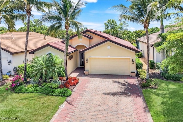 26304 Prince Pierre Way, Bonita Springs, FL 34135 - mediterranean / spanish-style home with a garage, stucco siding, decorative driveway, and a front yard