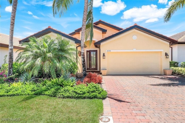 26304 Prince Pierre Way, Bonita Springs, FL 34135 - mediterranean / spanish home featuring stucco siding, a garage, and decorative driveway