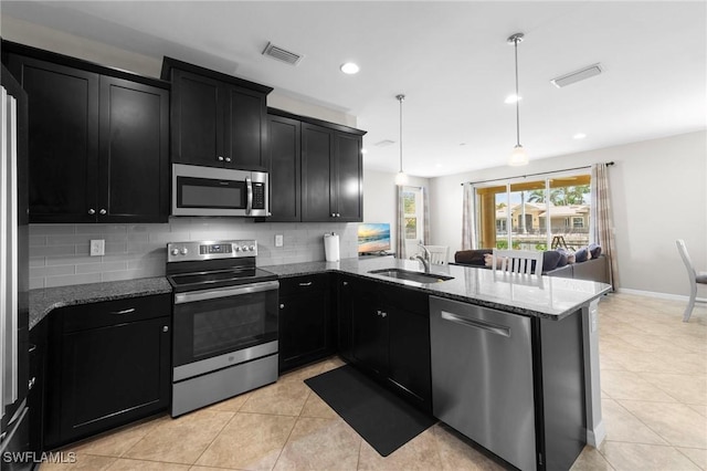 10844 Alvara Point Dr, Bonita Springs, FL 34135 - kitchen featuring stainless steel appliances, dark cabinetry, a sink, decorative backsplash, and a peninsula
