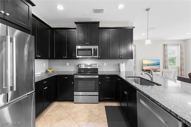 10844 Alvara Point Dr, Bonita Springs, FL 34135 - kitchen with stainless steel appliances, a sink, dark cabinets, stone countertops, and light tile patterned floors