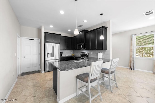 10844 Alvara Point Dr, Bonita Springs, FL 34135 - kitchen featuring appliances with stainless steel finishes, dark cabinets, dark stone counters, decorative backsplash, and a peninsula