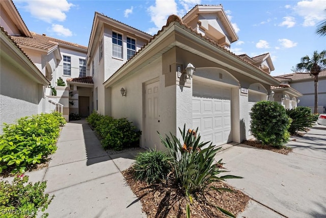 4410 Riverwatch Dr Unit 102, Bonita Springs, FL 34134 - view of front facade with an attached garage, stucco siding, a tiled roof, and concrete driveway