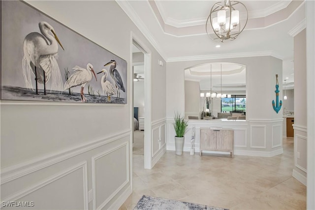 12732 Kinross Ln, Naples, FL 34120 - hall featuring a tray ceiling, a chandelier, a decorative wall, ornamental molding, and light tile patterned flooring