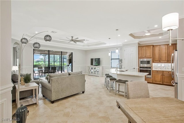 12732 Kinross Ln, Naples, FL 34120 - living area with a decorative wall, a ceiling fan, crown molding, a tray ceiling, and recessed lighting