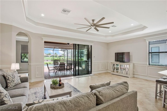 12732 Kinross Ln, Naples, FL 34120 - living area featuring a raised ceiling, a decorative wall, ceiling fan, light tile patterned floors, and arched walkways