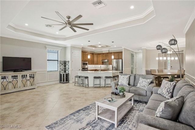 12732 Kinross Ln, Naples, FL 34120 - living room with a raised ceiling, a ceiling fan, ornamental molding, a decorative wall, and a chandelier