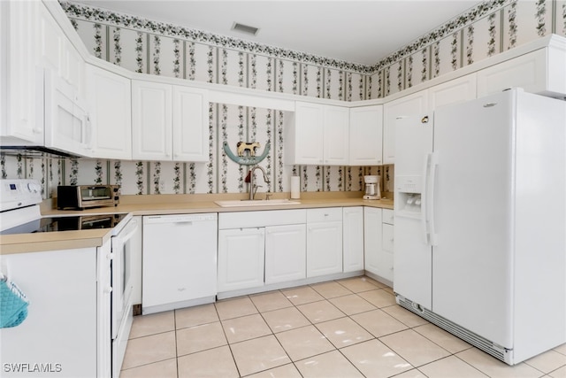 8515 Chase Preserve Dr, Naples, FL 34113 - kitchen featuring white appliances, a sink, wallpapered walls, white cabinetry, and light countertops