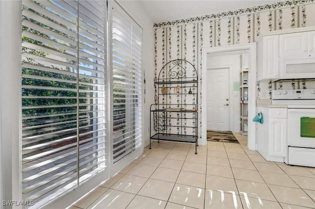 8515 Chase Preserve Dr, Naples, FL 34113 - kitchen with white range with electric cooktop, white cabinets, light tile patterned floors, and light countertops
