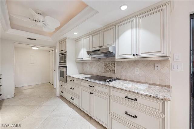 5964 Pelican Bay Blvd Unit 415, Naples, FL 34108 - kitchen with under cabinet range hood, stainless steel appliances, decorative backsplash, a tray ceiling, and recessed lighting