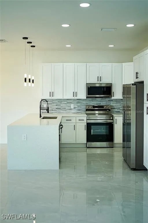 3017 4th St W, Lehigh Acres, FL 33971 - kitchen with stainless steel appliances, a sink, white cabinets, a peninsula, and tasteful backsplash