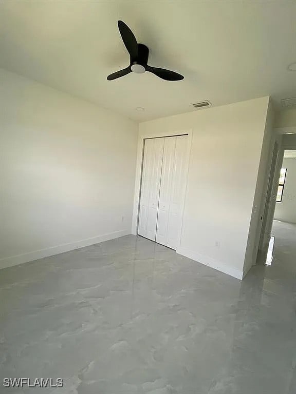 3017 4th St W, Lehigh Acres, FL 33971 - unfurnished bedroom with finished concrete flooring, baseboards, a closet, and a ceiling fan
