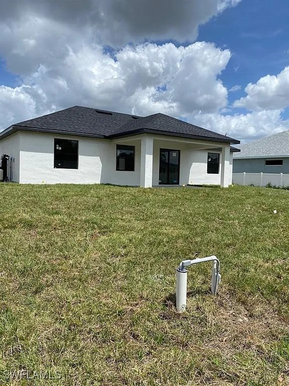 3017 4th St W, Lehigh Acres, FL 33971 - back of house with a lawn and stucco siding