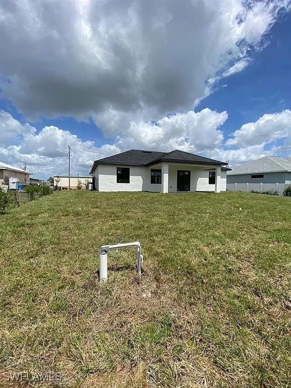 3017 4th St W, Lehigh Acres, FL 33971 - rear view of house with a yard and stucco siding