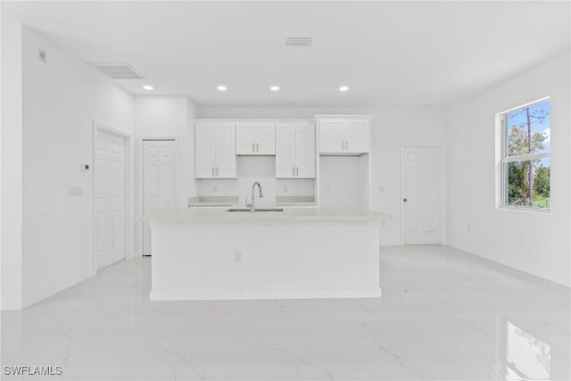 3507 41st St SW, Lehigh Acres, FL 33976 - kitchen with an island with sink, white cabinetry, a sink, recessed lighting, and light marble finish flooring