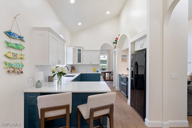 171 Via Napoli, Naples, FL 34105 - kitchen featuring black refrigerator with ice dispenser, arched walkways, a sink, light countertops, and light wood-style flooring