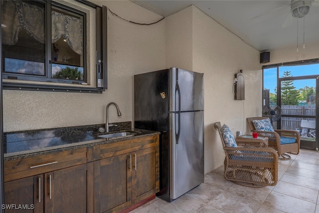 3460 4th Ave NE, Naples, FL 34120 - kitchen with freestanding refrigerator, a sink, a ceiling fan, dark brown cabinets, and dark stone counters