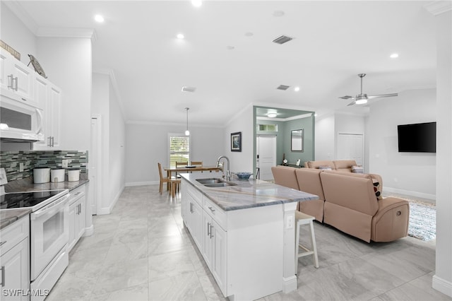 1187 16th Ave NE, Naples, FL 34120 - kitchen featuring white appliances, a sink, crown molding, baseboards, and a kitchen bar
