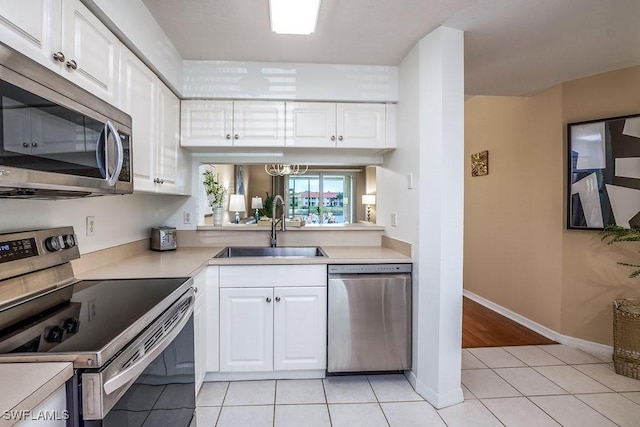 6900 Huntington Lakes Cir Unit 102, Naples, FL 34119 - kitchen with stainless steel appliances, a sink, light tile patterned flooring, and white cabinets