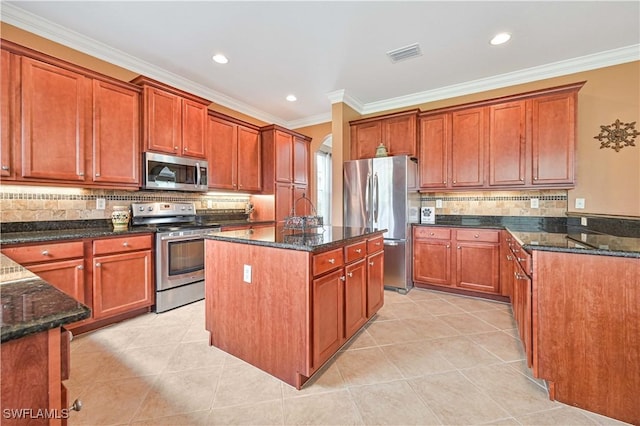 10212 Mimosa Silk Dr, Fort Myers, FL 33913 - kitchen featuring appliances with stainless steel finishes, dark stone countertops, ornamental molding, a kitchen island, and light tile patterned floors