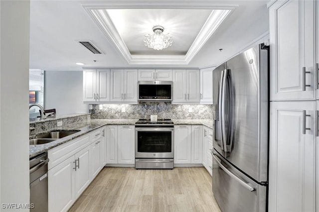 100 N Collier Blvd Unit 1002, Marco Island, FL 34145 - kitchen featuring appliances with stainless steel finishes, a sink, white cabinetry, light wood finished floors, and crown molding