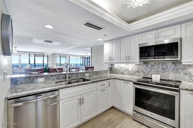 100 N Collier Blvd Unit 1002, Marco Island, FL 34145 - kitchen featuring stainless steel appliances, a sink, a chandelier, white cabinetry, and decorative backsplash
