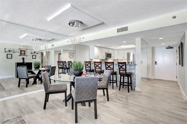 100 N Collier Blvd Unit 1002, Marco Island, FL 34145 - dining area with a textured ceiling, light wood-style flooring, a chandelier, and baseboards