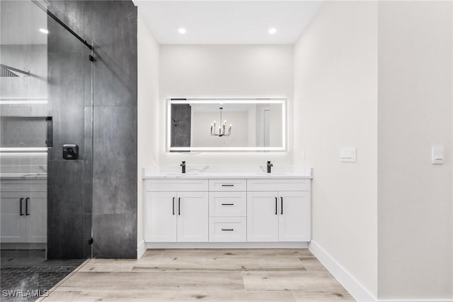 224 NW 14th Pl, Cape Coral, FL 33993 - bathroom with double vanity, wood finished floors, a chandelier, a shower with door, and baseboards