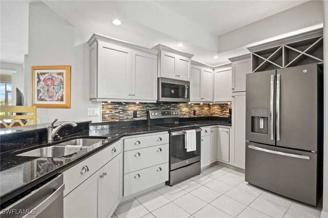 23581 Sandycreek Ter Unit 1107, Estero, FL 34135 - kitchen with stainless steel appliances, a sink, tasteful backsplash, light tile patterned floors, and dark stone counters