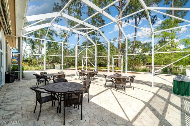 5135 Cobble Creek Ct Unit 204, Naples, FL 34110 - view of patio with glass enclosure and view of wooded area