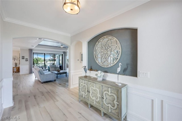 17476 Ashcomb Way, Estero, FL 33928 - corridor featuring arched walkways, a decorative wall, crown molding, a wainscoted wall, and light wood finished floors