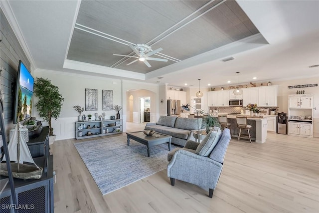 17476 Ashcomb Way, Estero, FL 33928 - living room featuring a raised ceiling, arched walkways, light wood-style floors, ornamental molding, and a ceiling fan