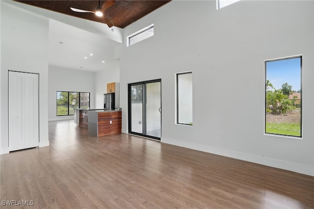 2815 45th St W, Lehigh Acres, FL 33971 - unfurnished living room featuring a high ceiling, ceiling fan, wood finished floors, and baseboards