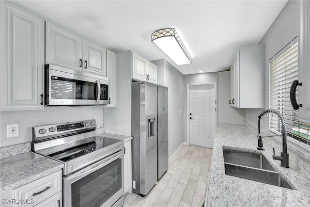 13820 2nd St, Fort Myers, FL 33905 - kitchen with stainless steel appliances, a sink, white cabinetry, light stone countertops, and baseboards