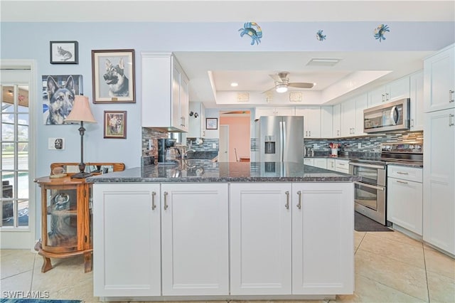 1826 SE 6th Ave, Cape Coral, FL 33990 - kitchen featuring appliances with stainless steel finishes, a tray ceiling, a peninsula, and tasteful backsplash