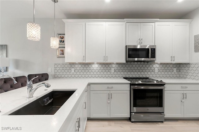 7619 Morgan Way, Naples, FL 34119 - kitchen featuring stainless steel appliances, a sink, backsplash, and decorative light fixtures