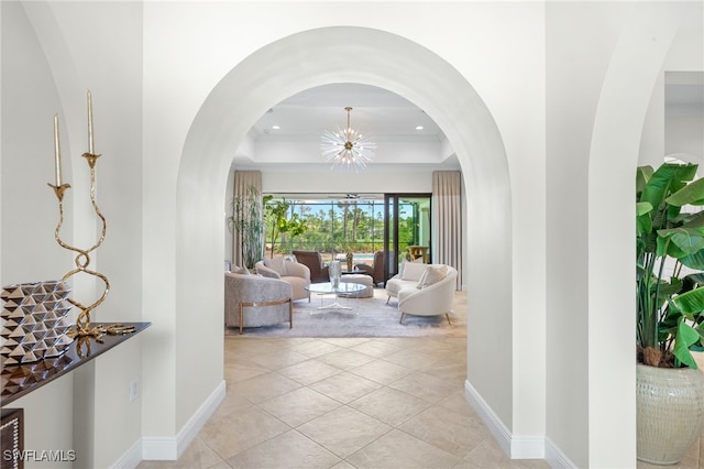 14500 Marsala Way, Naples, FL 34109 - corridor featuring a raised ceiling, a chandelier, baseboards, recessed lighting, and arched walkways