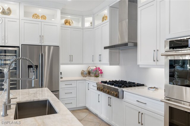 14500 Marsala Way, Naples, FL 34109 - kitchen featuring wall chimney range hood, stainless steel appliances, a sink, white cabinets, and light tile patterned floors